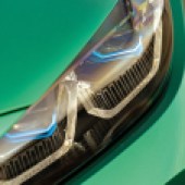 A close up of the front left headlight on an emerald green BMW M3