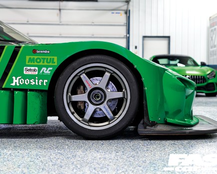 A close up of the front right wheel of a green Mazda Quad Rotor RX 7