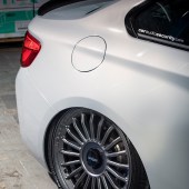 A close up of the rear right wheel and petrol hole of a white BMW M2